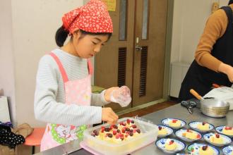 画像　ロールケーキにベリーを乗せる子ども